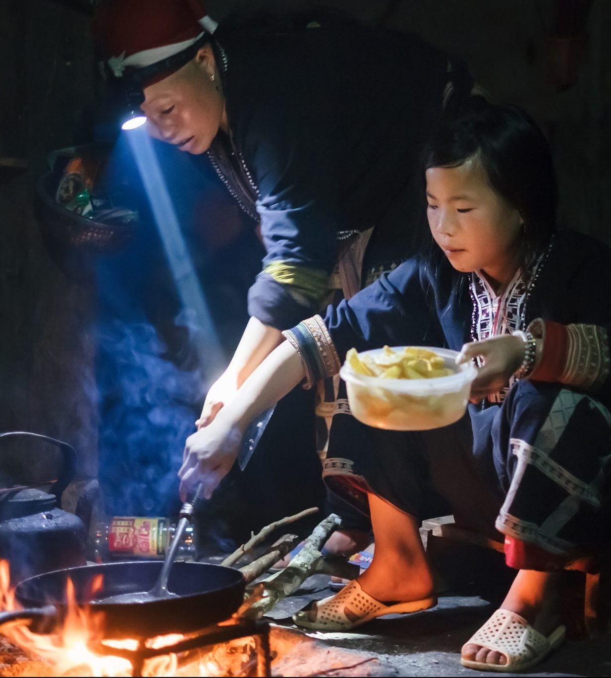 Man and woman cooking over open fire