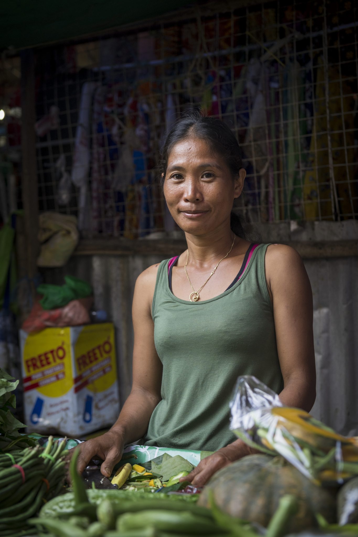 A Filipino market vendor looks up with a friendly smile while selling vegetables at the main market in Puerto Princesa, Palawan, Philippines. (July 3, 2019)