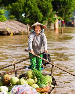 "Vietnamese fruits seller - woman rowing boat in the Mekong river delta &amp; selling fruits, Vietnam."