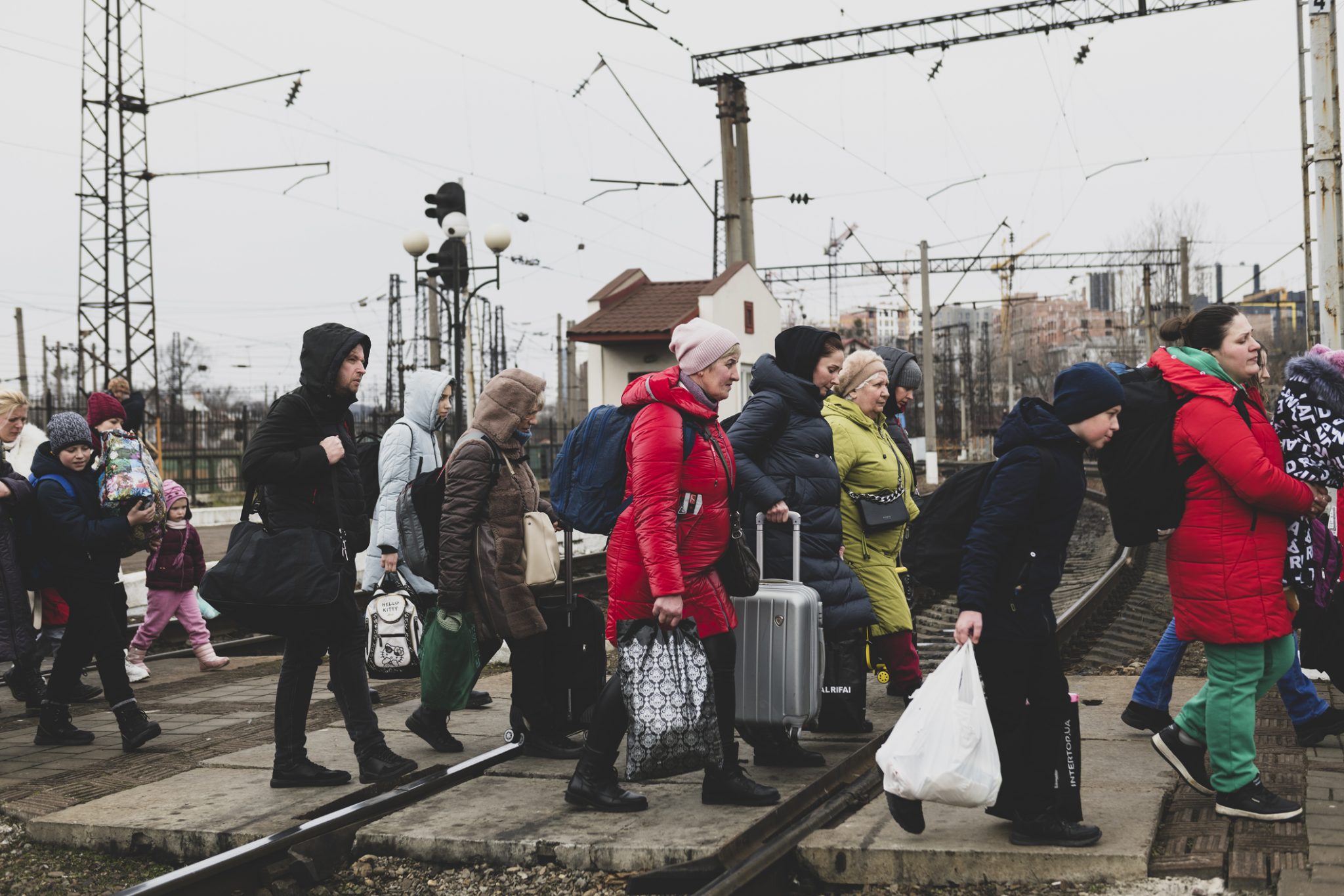 Lviv, Ukraine - March 3, 2022: Having just disembarked a train, people walk with their luggage across the tracks in Lviv.
